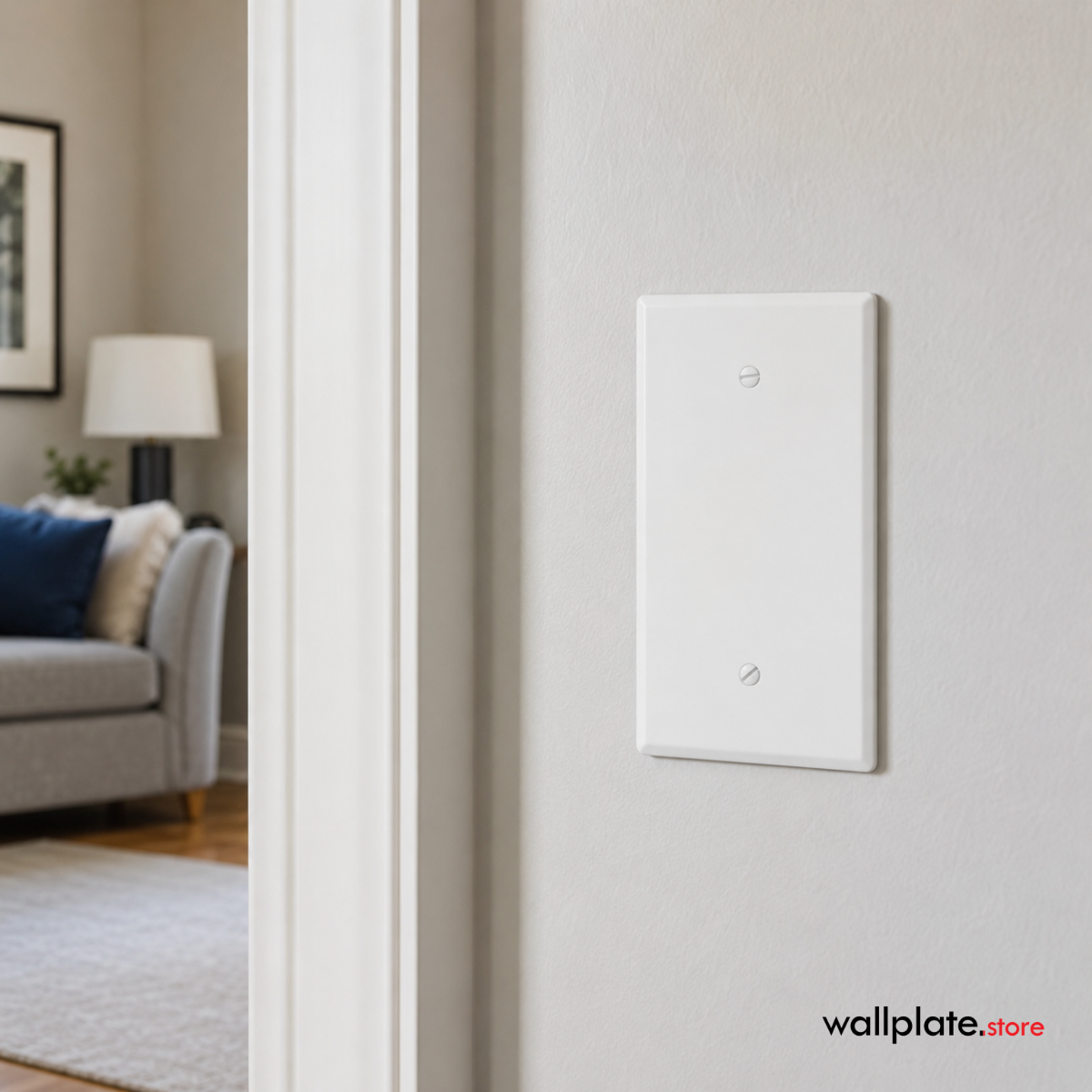 A white blank jumbo wall plate mounted on a textured off-white wall, with a softly blurred living room visible through an open doorway on the left.